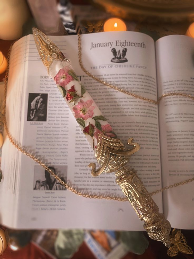 an open book on a table next to candles and a candle holder with a flowered handle