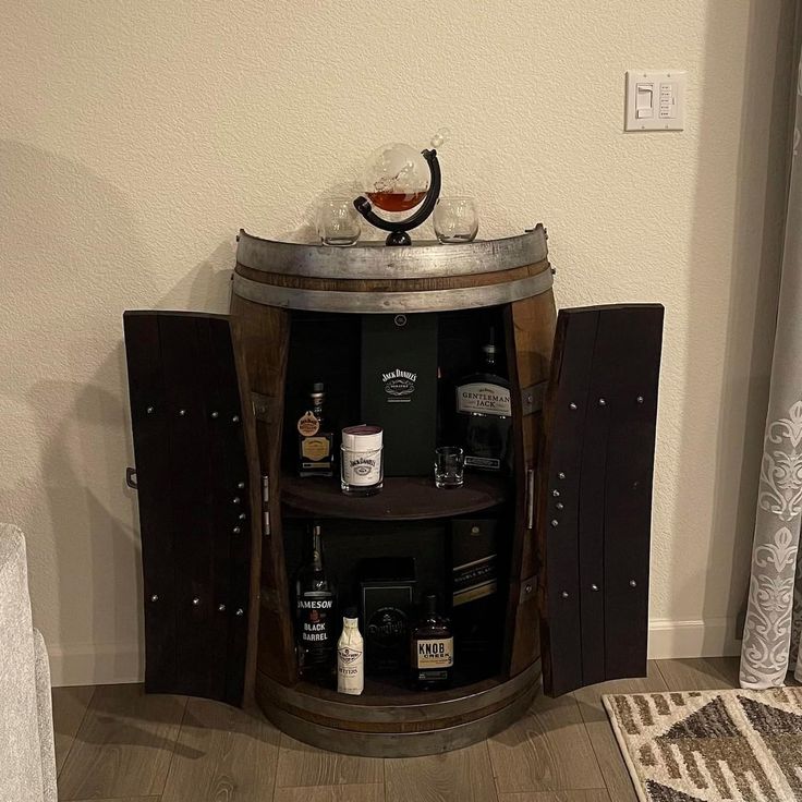 a wooden barrel with liquor bottles on it in front of a mirror and door to another room