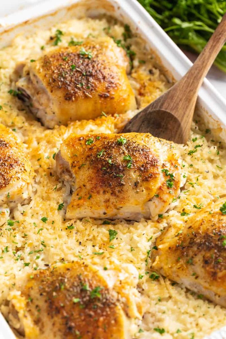 chicken and rice casserole in a white dish with a wooden spoon on the side