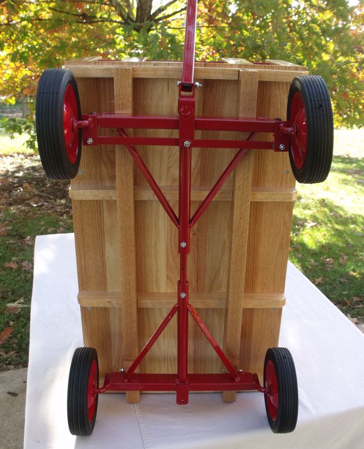 a wooden cart with wheels is sitting on a white tablecloth in front of some trees