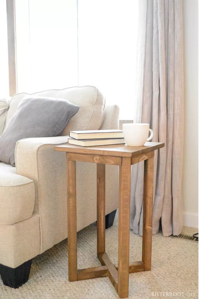 a white couch sitting next to a table with a book and cup on top of it