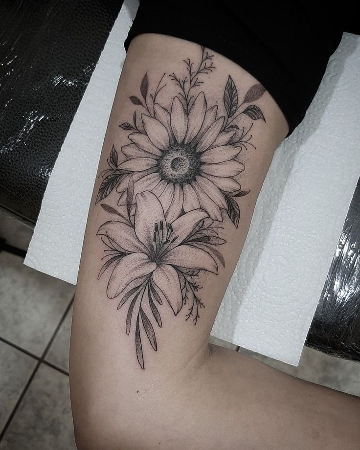 a black and white photo of a woman's leg with flowers on it,