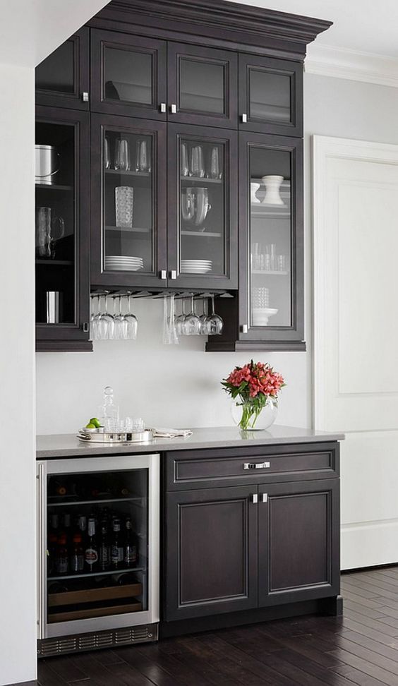 an empty kitchen with black cabinets and white walls, including a wine glass cabinet in the center