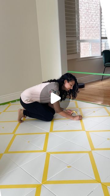 a woman kneeling down on the floor in front of a yellow and white checkered floor