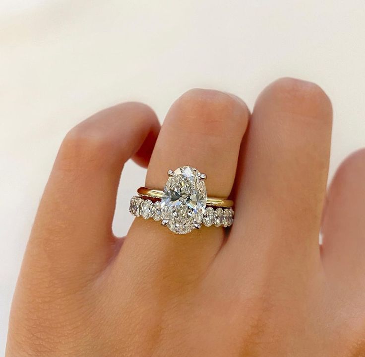 a woman's hand holding a ring with two diamonds on it and the middle finger