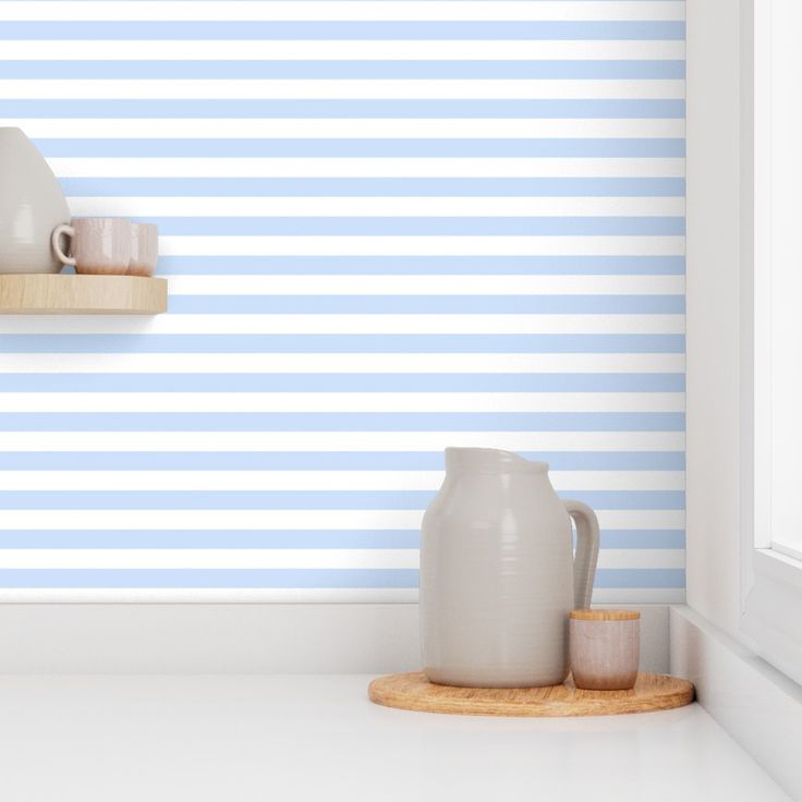 two white vases are sitting on a shelf in front of a blue striped wall