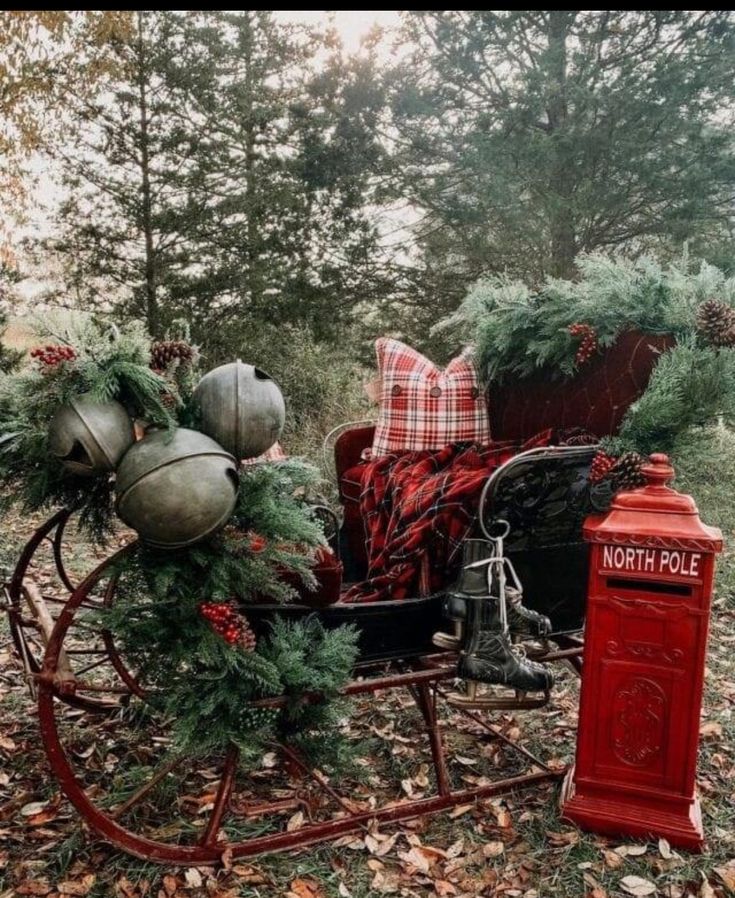 a horse drawn carriage with christmas decorations on it's back in the woods next to a red phone booth