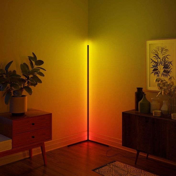 a lamp that is on in the corner of a room with a plant next to it