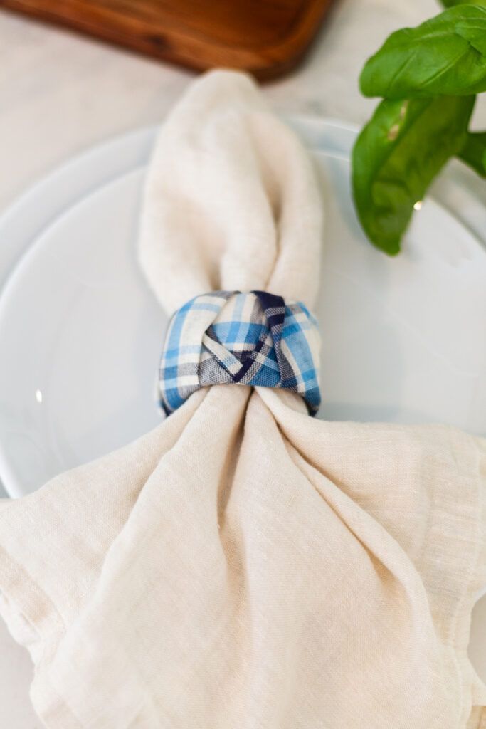 a white plate topped with a blue and white checkered napkin next to a green plant