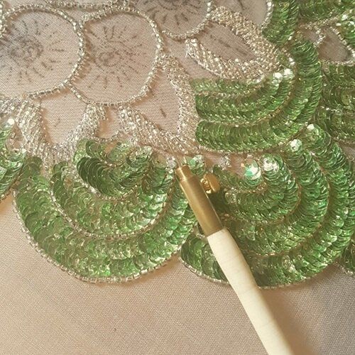 a close up of a table cloth with green sequins and a pen on it