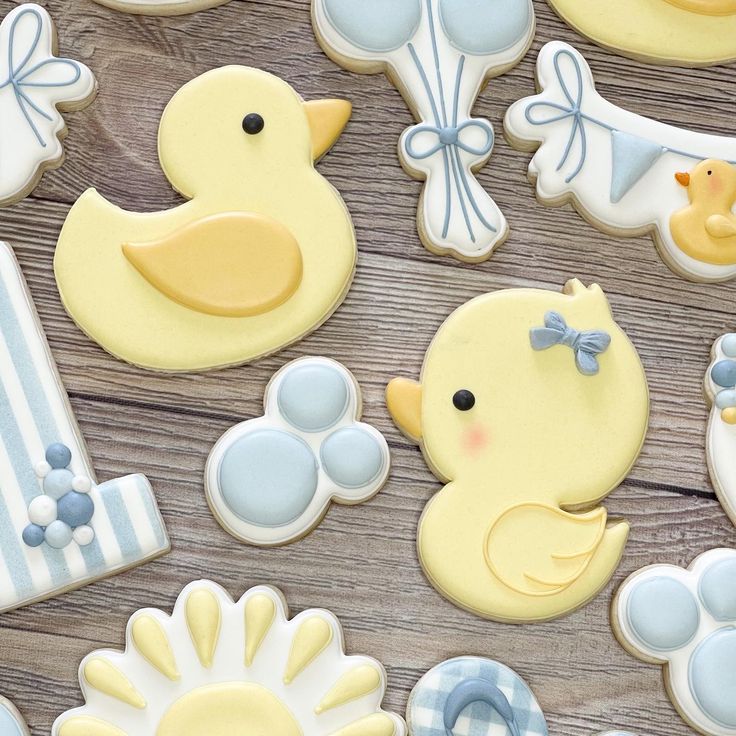 baby shower cookies are arranged on a wooden table with blue and white decorations, such as rubber ducks