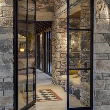 an open glass door leading into a stone building