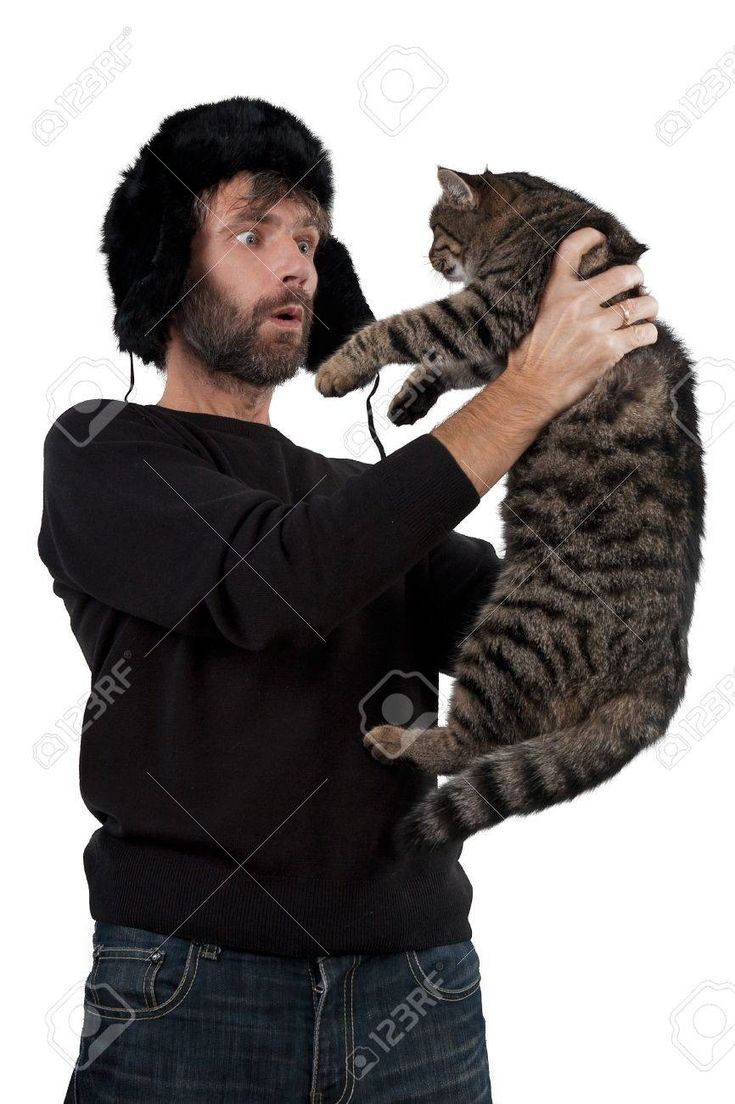 a man holding a cat in his arms and wearing a hat on top of it