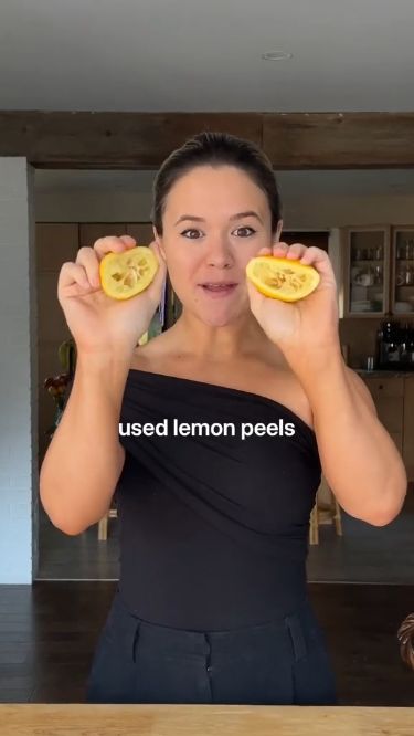 a woman holding two slices of lemons in front of her face with the words used lemon peels