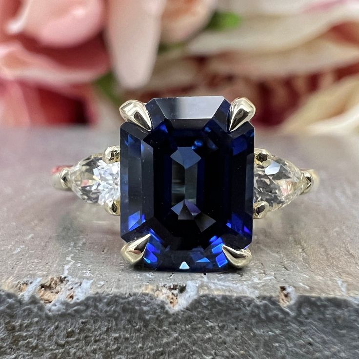 an image of a ring with a blue stone in the middle and two diamonds around it