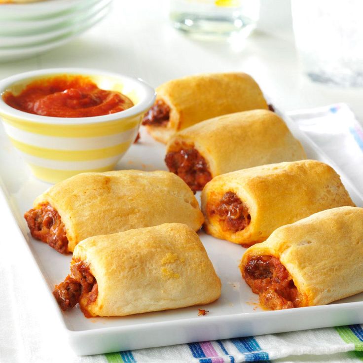 several pastries on a plate with sauce in a bowl next to it and another dish