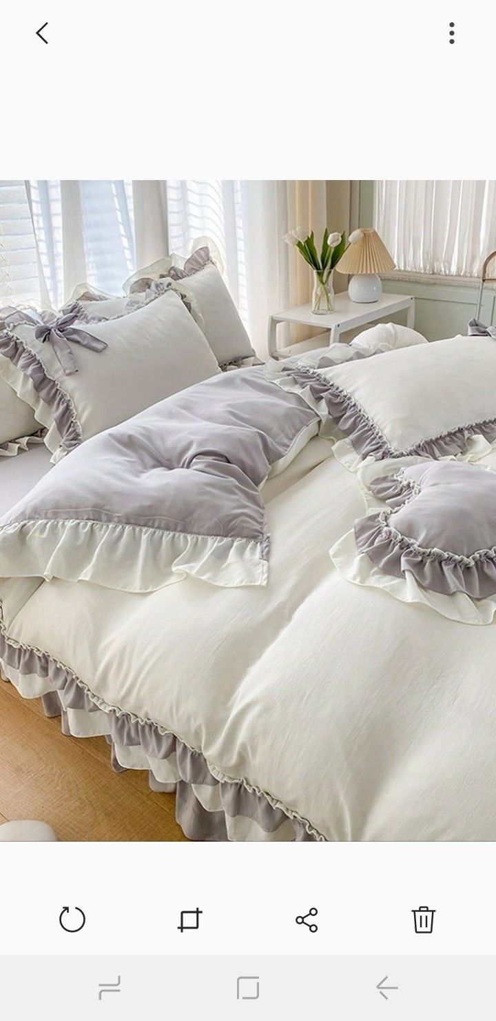 an image of a bed with ruffles and pillows on the bottom half of it