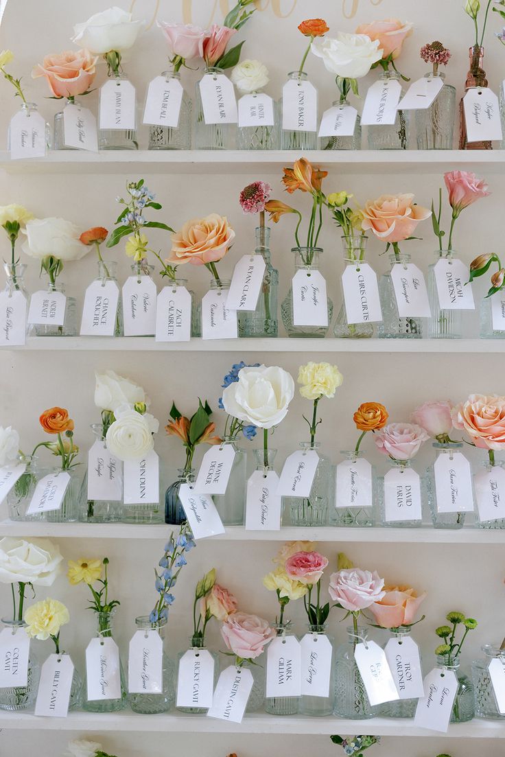 several rows of flowers are arranged on the shelves with name tags attached to each row