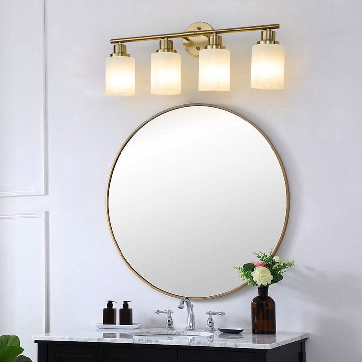 a bathroom vanity with a round mirror above it and lights on the wall next to it