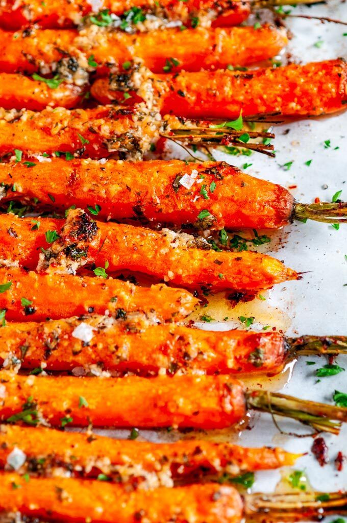 cooked carrots with herbs and seasoning sit on a baking sheet, ready to be served