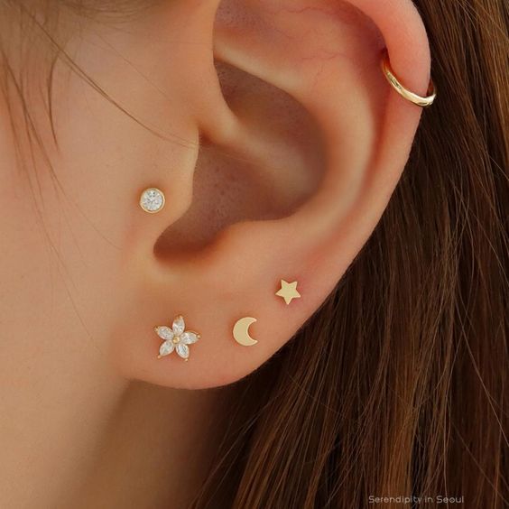 a woman's ear with three small stars and moon studs