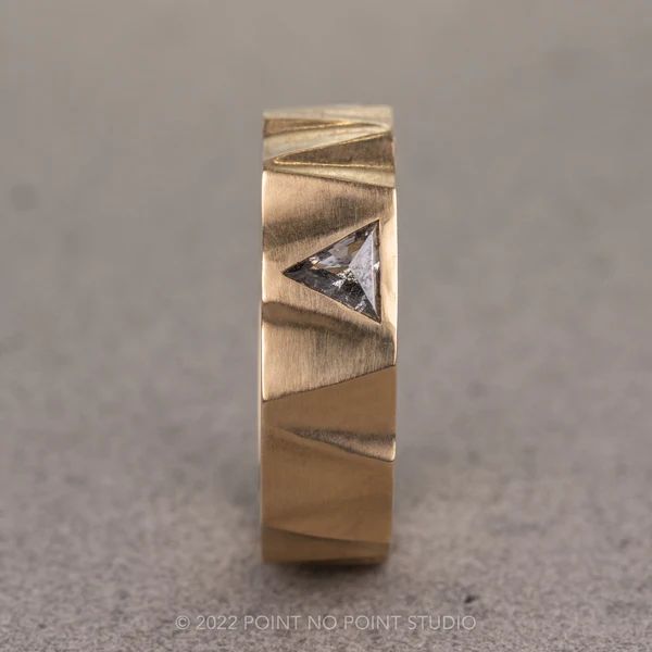 a gold wedding band with a diamond in the center