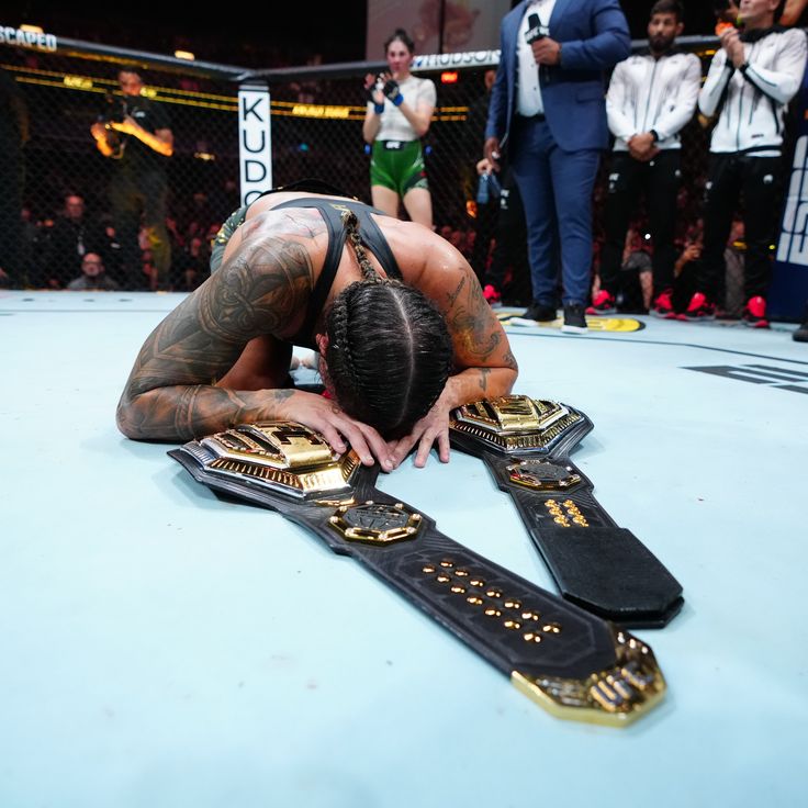 a man laying on top of a wrestling ring with his hands in the ground while others watch