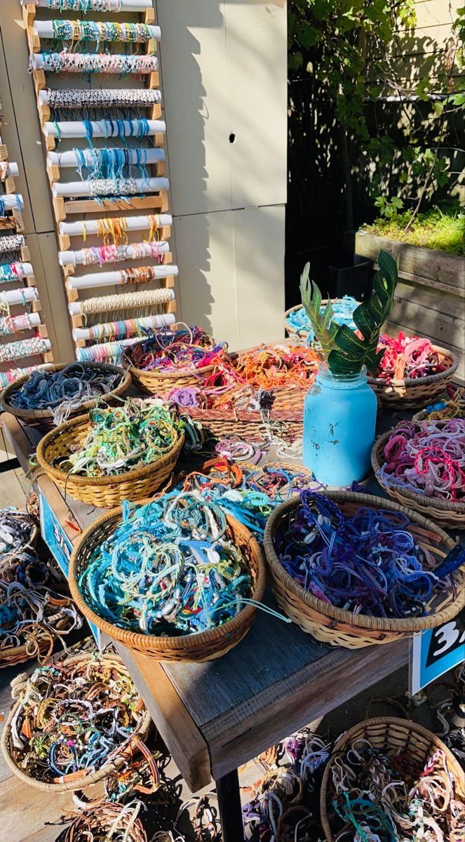 the table is covered with many different colored yarns and baskets full of them on it