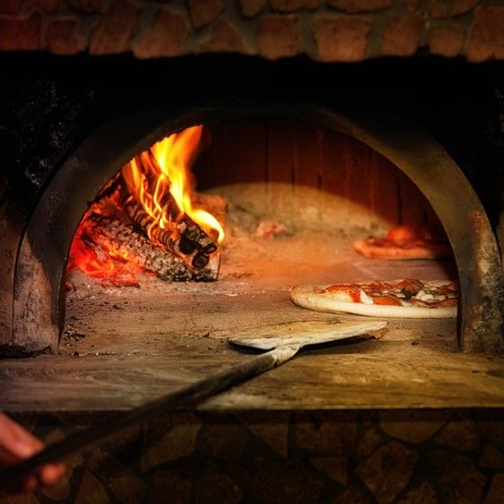 a pizza is cooking in an oven with fire coming from the top and on to the bottom