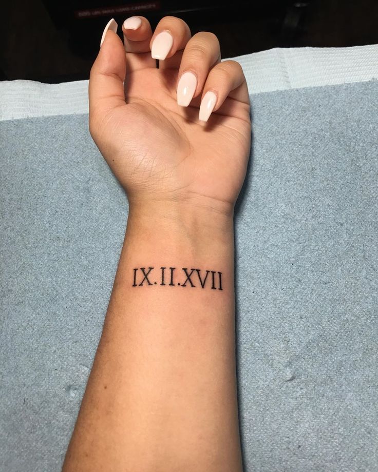 a woman's arm with the roman numeral tattoo on her left wrist, in black ink