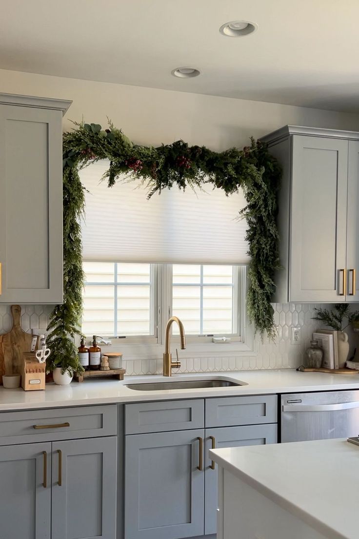 a kitchen decorated for christmas with wreaths and greenery on the window sill