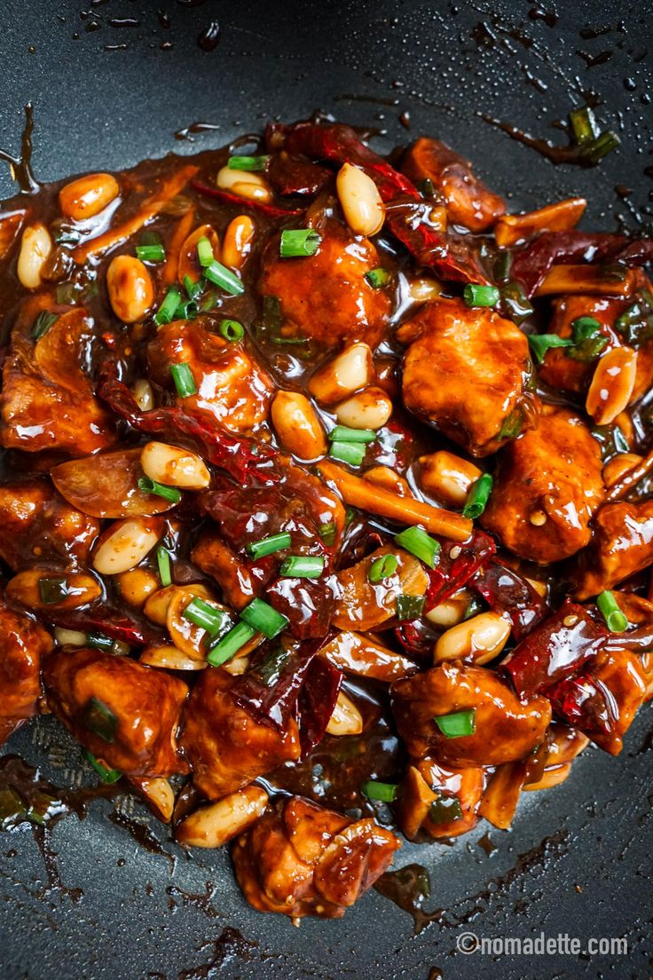 chicken and cashews are being cooked in a wok