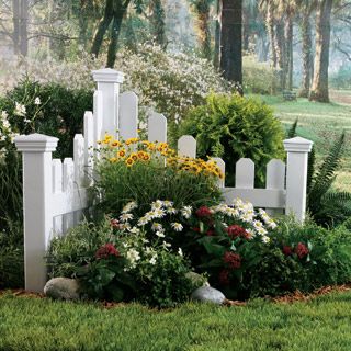 a white picket fence surrounded by flowers and trees