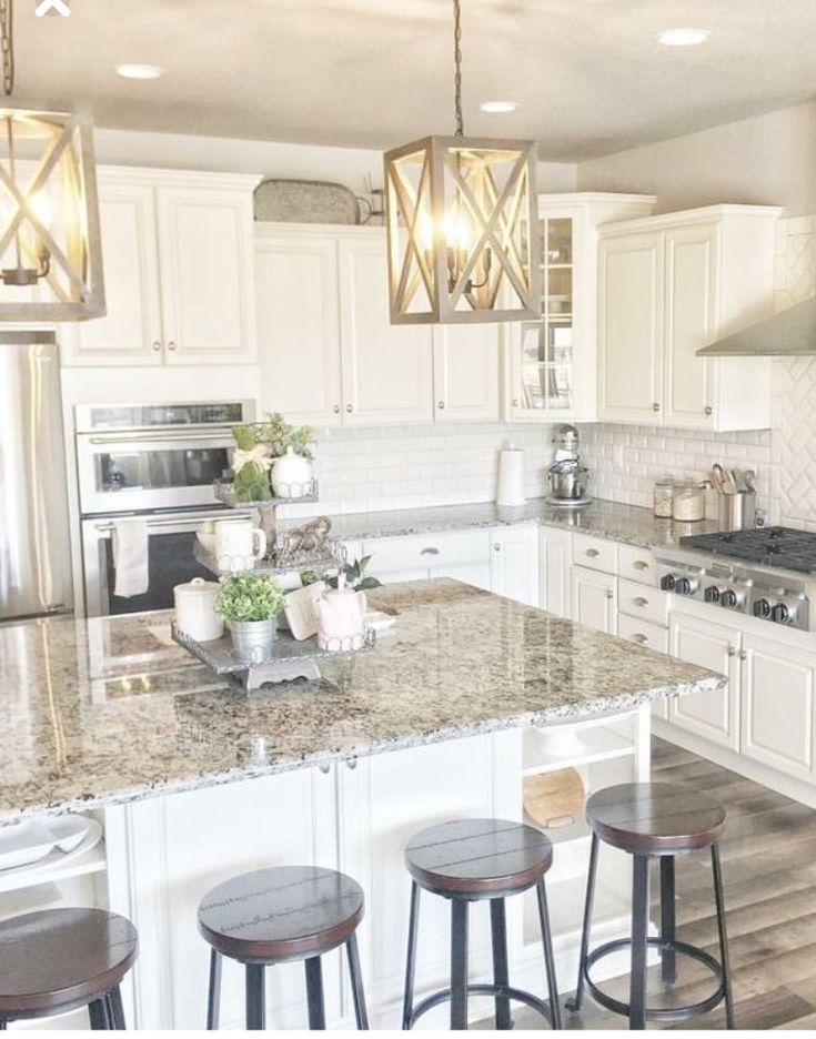 a large kitchen with white cabinets and marble counter tops, an island in the middle