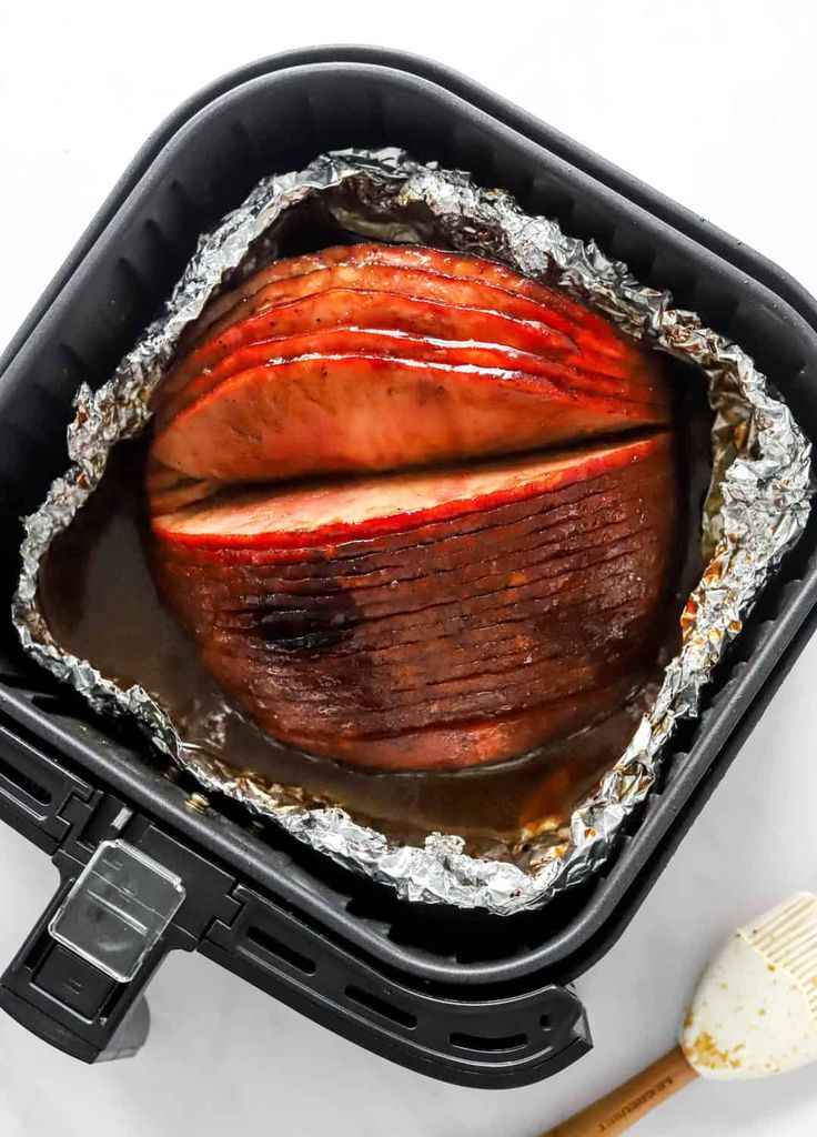 an open roasting pan filled with food and a spatula next to it on a white surface