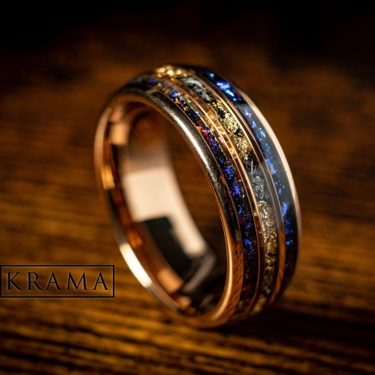 a gold ring with multicolored stones in it on top of a wooden table