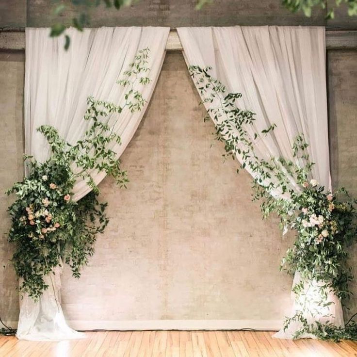 an image of a wedding stage setting with flowers and greenery on the curtained wall