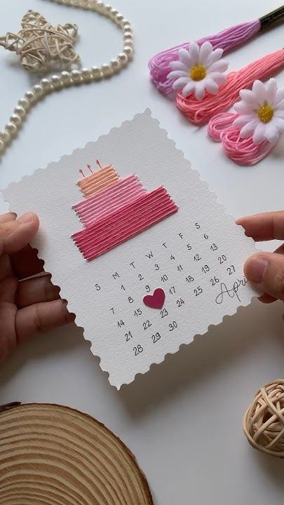 someone is holding up a card with a cake on it and flowers in the background