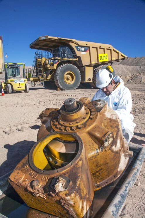 a man sitting on top of a yellow fire hydrant in the middle of a dirt field