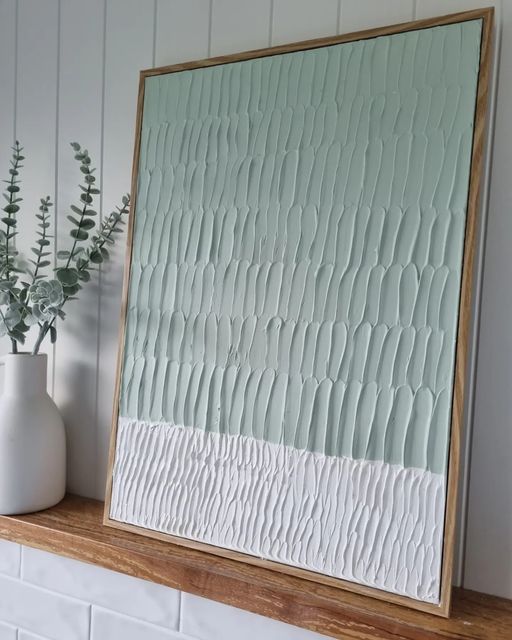 a white vase sitting on top of a wooden shelf next to a wall mounted mirror