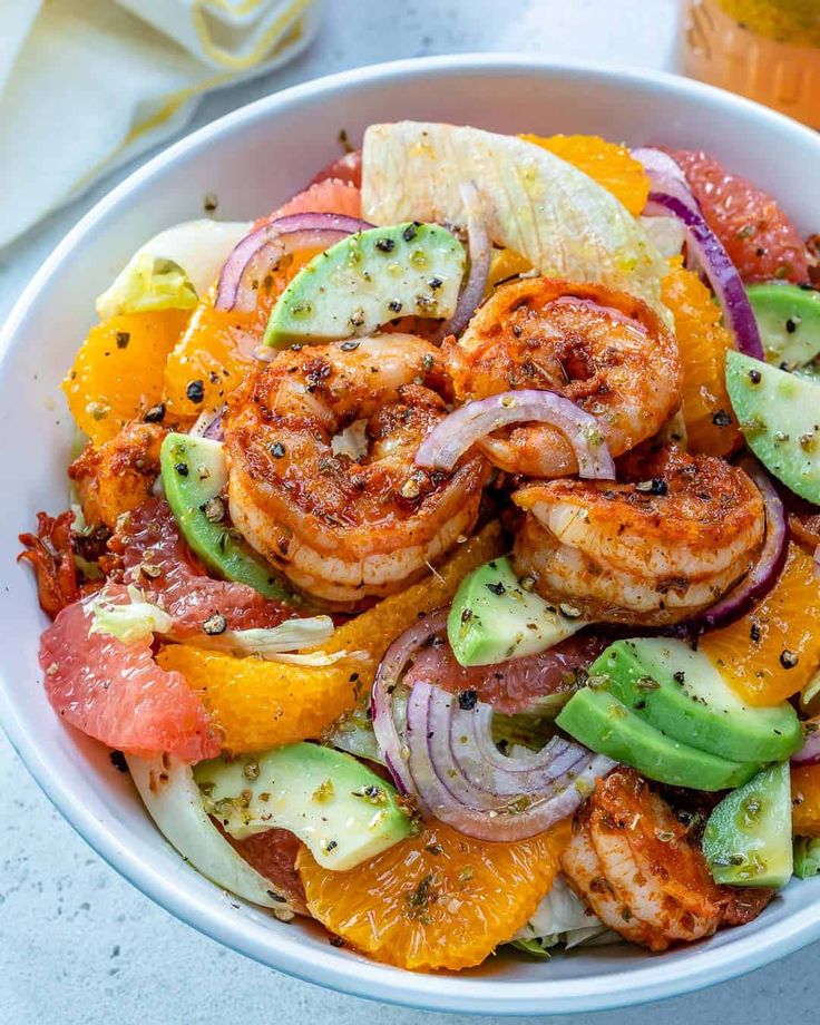 a white bowl filled with shrimp, oranges and onions