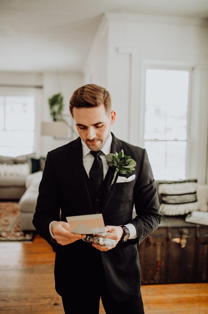 a man in a tuxedo looking at a piece of paper with a boutonniere on it