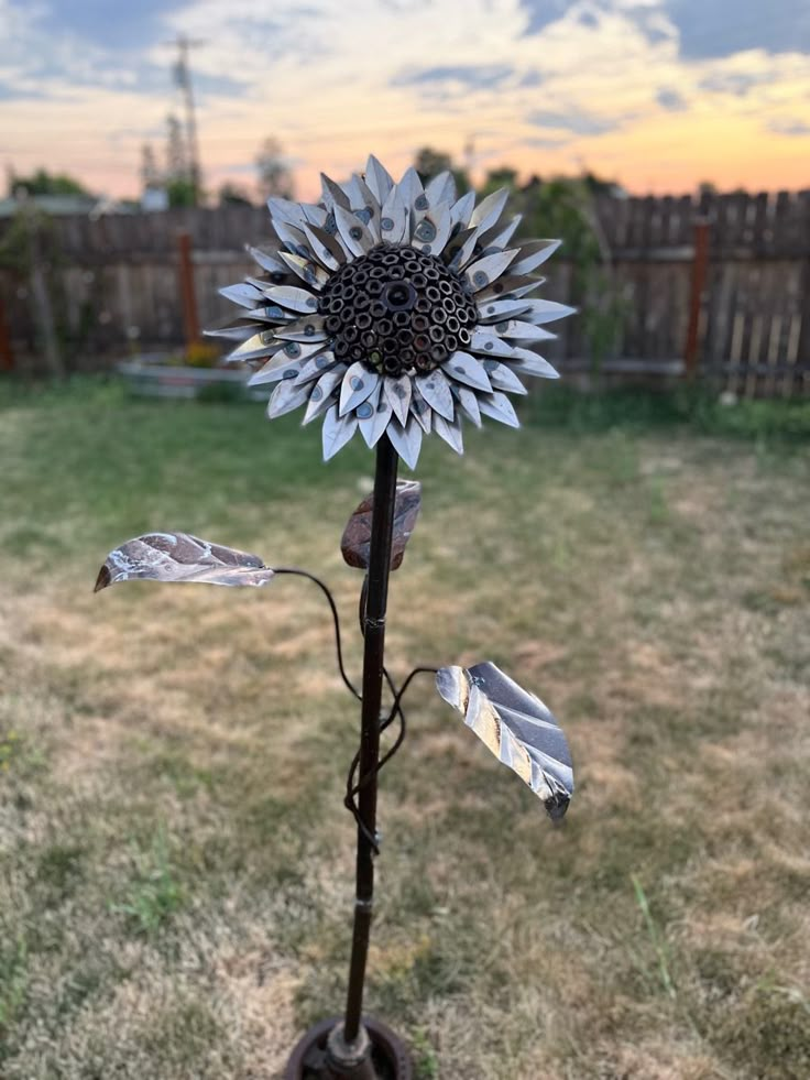 a metal sunflower sitting in the middle of a yard