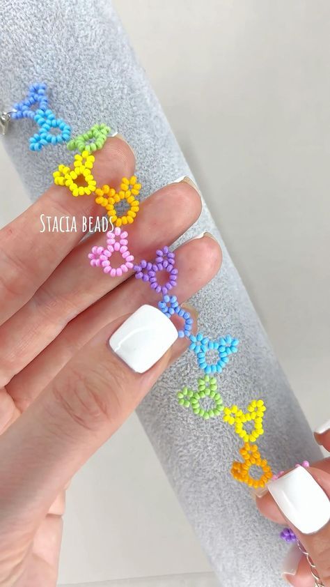 a woman's hand with white fingernails and colorful flowers on it, next to a silver tube