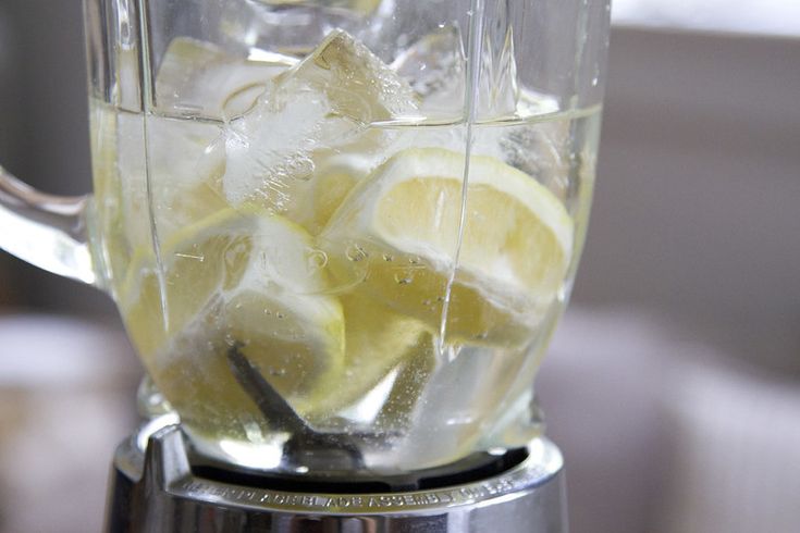 a blender filled with ice and lemon slices