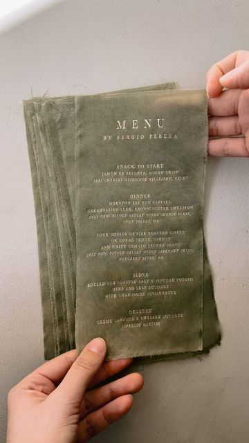 two hands holding up a menu on top of a table