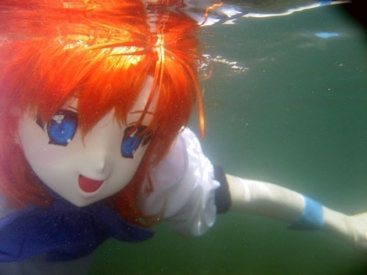 a girl with red hair and blue eyes swims under water