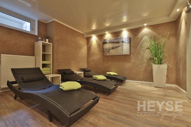 an indoor spa room with chaise lounges and potted plant in the corner