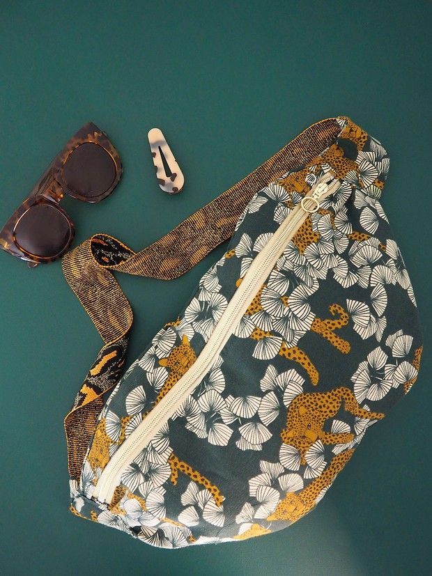 a purse, sunglasses and comb on a green surface with a pair of glasses next to it