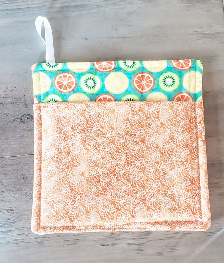 an orange and green bag sitting on top of a wooden table next to a pair of scissors